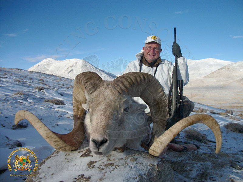 Snow covered mountains are in the back ground of this Marco Polo Argali Hunting picture that shows a hunter with his recent harvest.